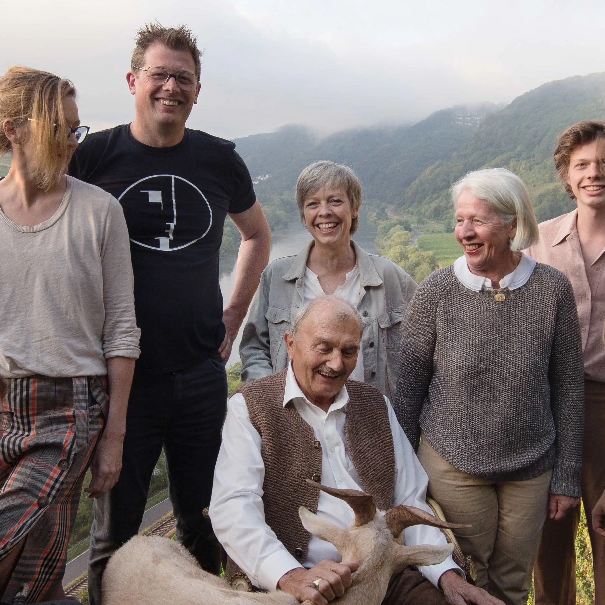 Wijnmakers van Weingut Melsheimer poseren met een fles Reiler Mullay-Hofberg Riesling Beerenauslese in de wijngaard in de Moezel, symbool voor ambachtelijke wijntraditie en passie voor duurzame Riesling-wijnen.